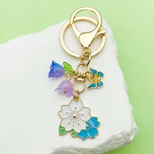 Macro detail of a Sakura cherry blossom keychain with bell flower and butterfly charms.