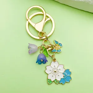 Detailed view of cute cherry blossom and butterfly charms on a golden metal keychain pendant