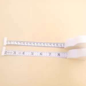 Detail of white retractable tape measure showing dual scale in centimeters and inches