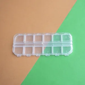 Vista superior detallada de caja transparente de 12 rejillas con tapas numeradas individuales.