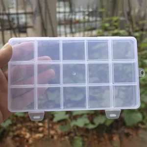 Close-up of a transparent 15-compartment plastic storage box held by a hand outdoors