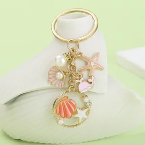 Close-up detail of ocean-themed keychain featuring enamel starfish, shell and whale charms