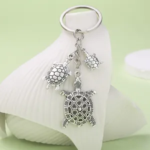 Detail view of ocean series turtle keychain with three alloy charms on a shell prop.
