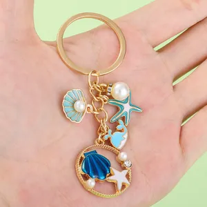 Close-up of a hand-held ocean-themed keychain featuring starfish and seashell charms