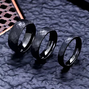 Detailed view of three black hammered tungsten carbide rings in various widths