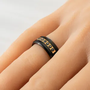 Detailed macro view of 8mm black tungsten steel ring with gold inlay and black zircons