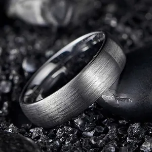 Macro detail of a 7mm wide brushed silver tungsten carbide ring for men on black stones.