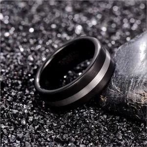 Detail of an 8mm black and silver brushed tungsten carbide ring for men on a dark stone background.