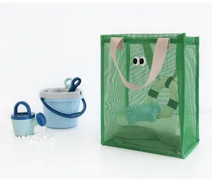 Detailed view of a green mesh beach bag with cute eyes and toy buckets on white background