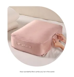 Close-up view of a large pink fabric storage bag being zipped up on a cozy white bed.