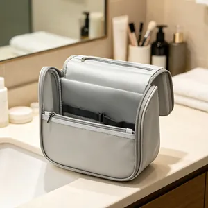 Neceser de viaje gris espacioso con compartimentos organizados sobre un lavabo de baño moderno