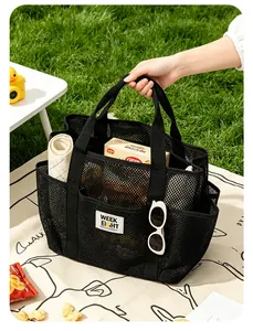 Grand sac de plage en maille noire porté à la main pour pique-nique et voyage