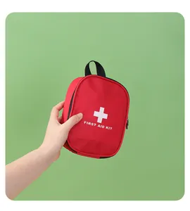 Vue détaillée d'une main tenant une trousse de secours rouge avec une croix blanche.