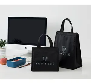 Vue détaillée de deux sacs à lunch isothermes noirs sur un bureau blanc avec accessoires