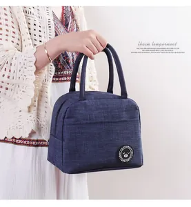 Isolierte dunkelblaue Lunchtasche mit Bären-Patch, gehalten von einem Modell im Häkel-Top