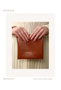 Close-up of a brown portable storage pouch held by hands for sanitary napkins