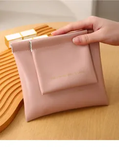 Detailed view of a portable pink leather pouch with embossed text on a wooden tray