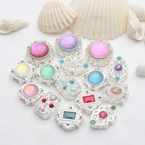 Vista detallada de dijes plateados con piedras de colores para crear joyas DIY únicas
