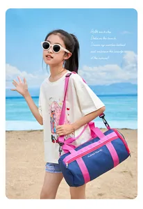 Young girl carrying a stylish blue and pink waterproof beach swim bag on a sunny beach