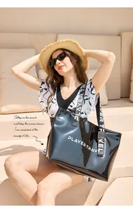 Stylish black waterproof swimming bag with 'PLAYER TRAVEL' logo shown by model at the beach