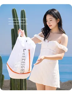 Modelo con bolsa de playa de malla blanca con cremallera naranja y compartimento.