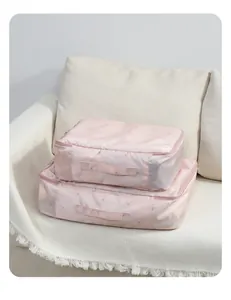 Nahaufnahme von zwei rosa gesteppten Reise-Organizer-Taschen auf einem beigen Sofa.