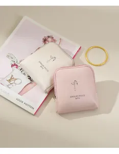 Close-up of pink and beige portable jewelry pouches with printed hand illustration
