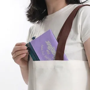 Portable travel anti-theft passport pouch shown being placed into a canvas tote bag