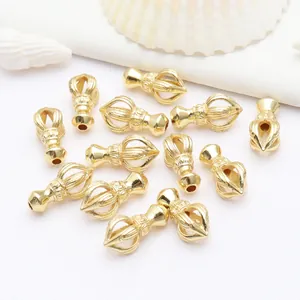 Primer plano de pequeños dijes dorados de mortero Vajra para la creación de joyas DIY.