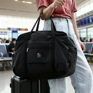 Large capacity waterproof black folding travel duffel bag carried in airport setting.