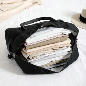 Große schwarze wasserdichte Reisetasche faltbar mit gefalteter Kleidung zur Aufbewahrung.