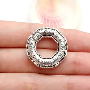 Close-up of vintage Tibetan silver circular charm with ornate floral patterns