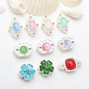 Macro detail of various silver-plated hollow spacer beads with colorful stones and rhinestones