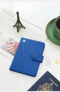 Blue PU leather passport holder with airplane icon in a travel-themed flat lay setting