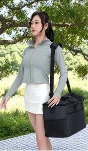 Asian model carrying a black 25L insulated cooler bag during an outdoor picnic trip