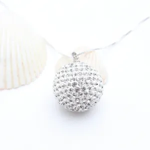 Close-up macro view of a sparkling rhinestone paved ball pendant on a fine silver link chain