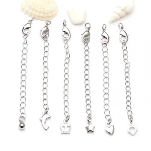 Detalle de cadenas de extensión plateadas con cierre de mosquetón y varios colgantes