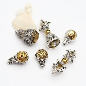 Nahaufnahme von antiken tibetischen Silberanhängern mit Vajra-Stößel, Glocke und Gravuren.
