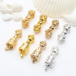 Macro detail of golden and silver Vajra pestle and bell charms for DIY jewelrymaking
