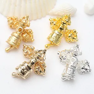 Detail view of intricately engraved gold and silver Vajra bell charms for jewelry making.