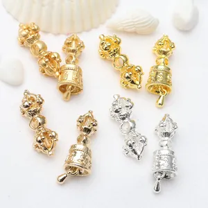 Detailed macro view of gold and silver Buddhist Vajra and Ghanta bell charms for DIY jewelry.