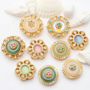 Primer plano de varios dijes de oro antiguo con piedras de jade sintéticas para joyería.