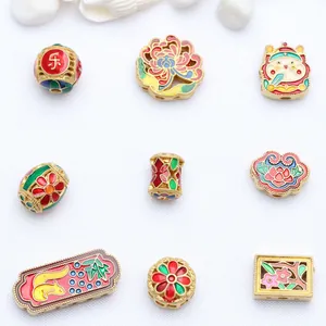 Detailed view of antique gold enamel beads with various floral and lucky motifs for DIY jewelry.