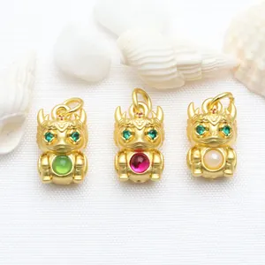 Detailed view of three antique gold dragon zodiac pendants with green, red, and pearl inlays.