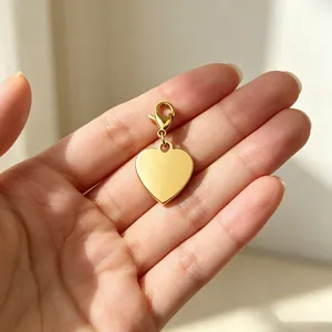 Detailaufnahme eines polierten goldenen Herzanhängers in der Hand mit Karabinerverschluss