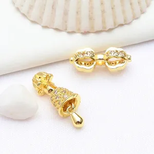 Close-up of gold Vajra pestle and bell charms with inlaid zircons for jewelry DIY