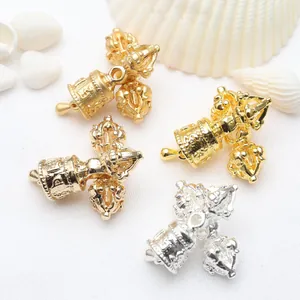 Macro view of intricately designed gold and silver Vajra bell charms for DIY jewelry.