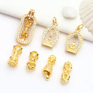 Detailed view of gold-plated Buddhist jewelry charms with Vajra and Buddha statue designs
