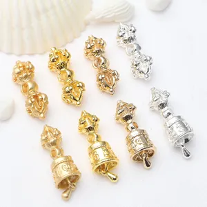Detailed view of antique gold and silver Vajra pestle and bell charms for DIY jewelry.