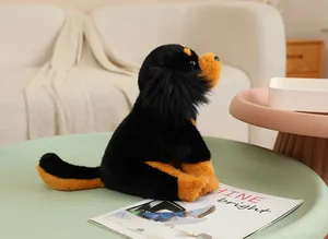 Detailed side view of a realistic black and tan plush dog toy on a minimalist green table